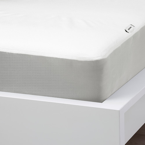 Protector de colchón impermeable con borde estampado sobre cama blanca.