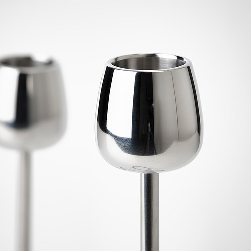 Dos candelabros de acero inoxidable elegantes y brillantes con superficies pulidas y líneas suaves y curvas. Uno en primer plano, otro borroso en el fondo.