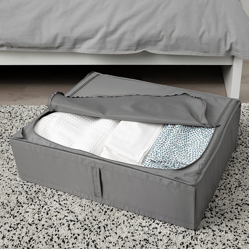 Caja de almacenamiento gris debajo de la cama con la tapa abierta, mostrando la ropa de cama doblada en el interior. Ideal para guardar ropa o ropa de cama de temporada, manteniéndola libre de polvo.