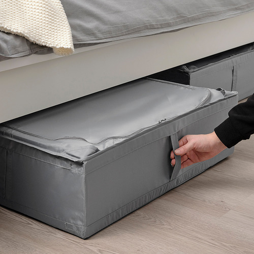 Persona tirando de una caja de almacenamiento debajo de la cama SKUBB gris, ideal para almacenar artículos de temporada, protegerlos del polvo y ahorrar espacio.