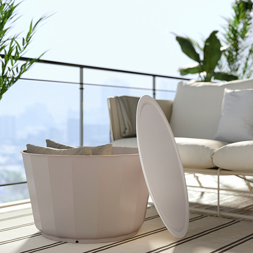 Ambiente exterior minimalista con sofá beige, papelera blanca, barandilla de cristal y vegetación.
