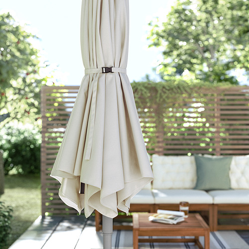 Sombrilla de patio beige cerrada sobre muebles de exterior.