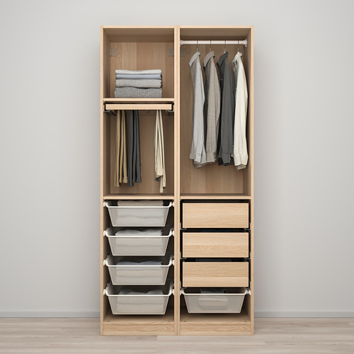Armario de madera abierto que muestra ropa organizada: camisas colgadas, suéteres doblados y cestas de almacenamiento grises.