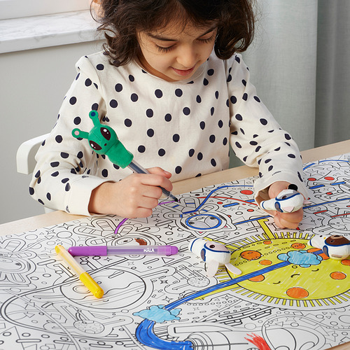 Una niña utiliza títeres de dedo para colorear un mantel individual con temática espacial, participando en un juego creativo.