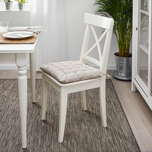 Una silla VIPPÄRT con almohadilla blanca cerca de la mesa del comedor, más pequeña que una planta en maceta.