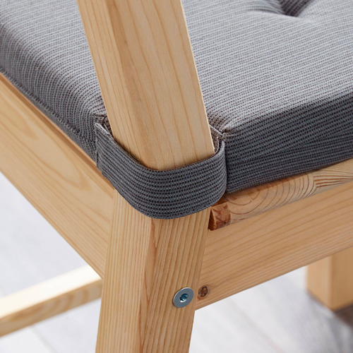 Primer plano del cojín de silla JUSTINA con cierres táctiles y patas de silla de madera.