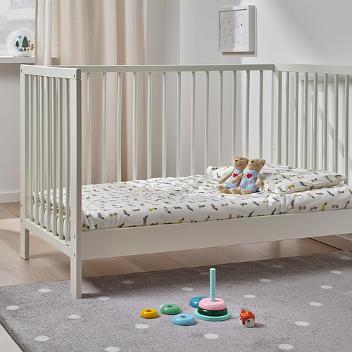 Cuna para bebés con ositos de peluche, colorido juguete apilable y alfombra de lunares. Obras de arte en la pared.