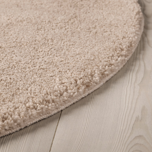 Primer plano de una alfombra con textura de terciopelo sobre suelo de madera, que muestra su pelo grueso y suave y su sutil brillo.
