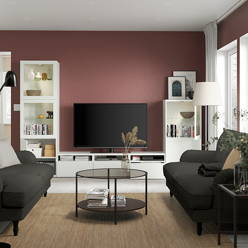 Sala de estar moderna con paredes granates, mueble de TV BESTÅ, 2 sofás grises, mesa de centro, lámpara de pie.