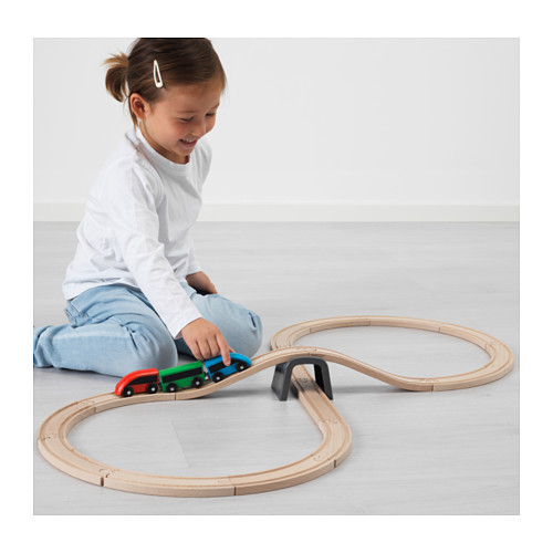 Niño jugando con el juego de trenes LILLABO, conectando vagones magnéticos en vías de madera.