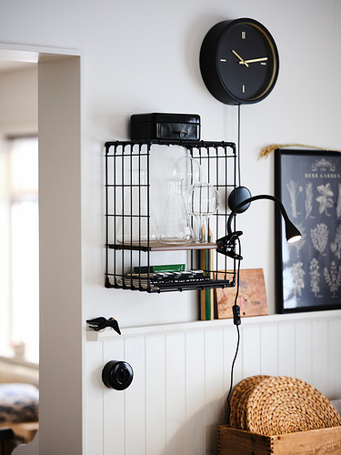Habitación moderna con reloj negro, estante de cristalería y lámpara de abrazadera en la pared de tablero de cuentas.