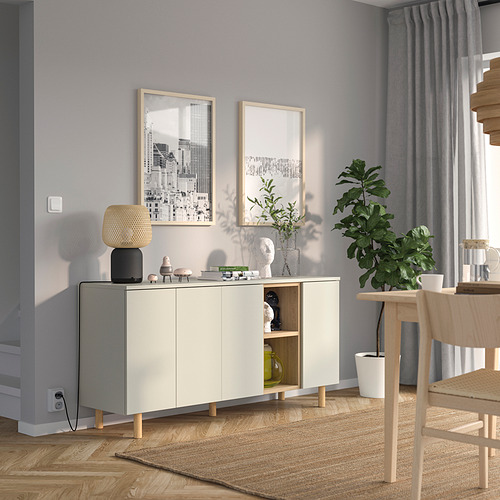 Mueble blanco LEDAMOT, estrecho para espacios pequeños, estantes abiertos en la parte superior, compartimentos en la parte inferior cerrados, entre el arte de la pared, la mesa y las cortinas.