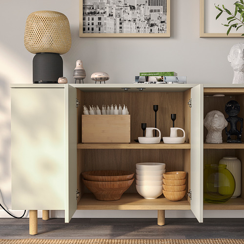 Armario moderno con almacenaje abierto y cerrado. Cuencos, tazas y velas cuidadosamente organizados, con diseño minimalista y patas de madera.