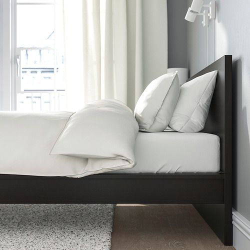 Estructura de cama con cabecero alto, ropa de cama blanca, espacio debajo de la cama, ventana adyacente.
