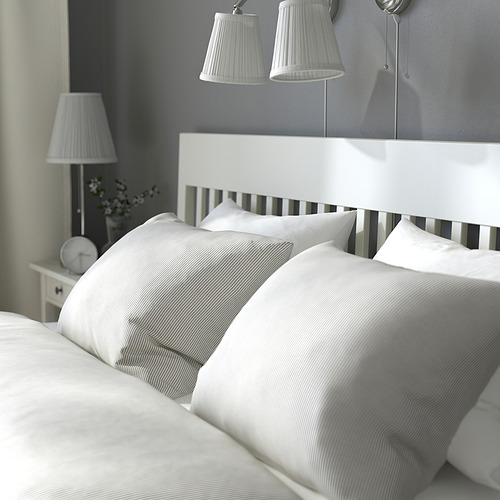 Cama moderna con cajones de almacenaje, altura regulable, lámparas de pared, mesita de noche con flores.