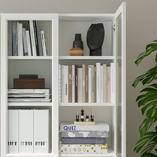 Estantería blanca con puertas de vidrio que exhibe libros, artículos decorativos y juegos; Estantes ajustables en el interior.