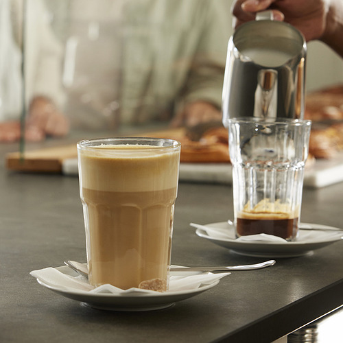Dos cafés, uno servido, con cucharas y servilletas.