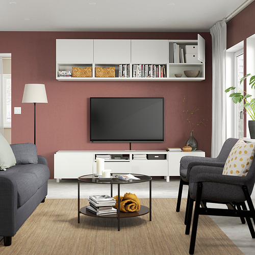Sala de estar moderna con mueble de TV BESTÅ, sofá gris, cojín de lunares, mesa de centro de cristal y gran ventanal.