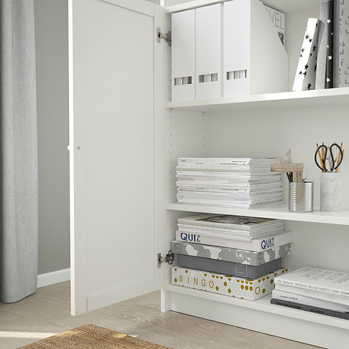 Estantería blanca con puerta abierta, que muestra archivos y libros organizados.