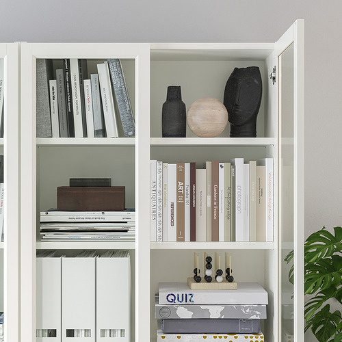Moderna estantería blanca con estantes ajustables, objetos decorativos y libros. Puertas de vidrio en la parte superior.