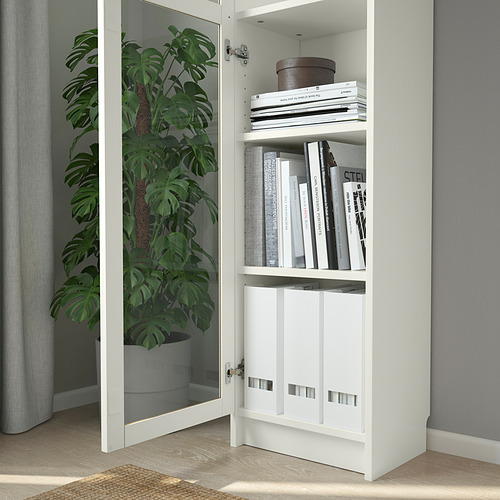 Librería BILLY con puerta de cristal, libros, planta.