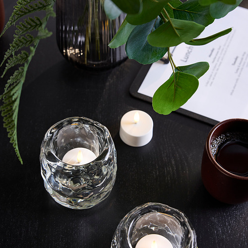 Tablero negro con candelita SKATGÅS , vela de té, planta, jarrón y plato.