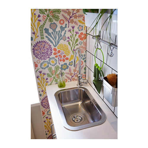 Cocina luminosa con papel pintado floral, con fregadero de acero inoxidable, grifo cromado y dispensador de jabón verde.