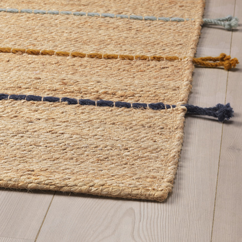 Alfombra plana de yute con rayas de hilo tejido. Natural y colorido, hecho a mano, se coloca sobre suelo de madera.