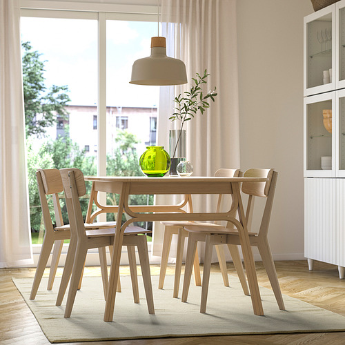 Modern dining table & chairs, green plant, window view, cabinet.