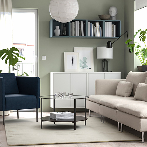 Modern living room with TIDTABELL table, rug, blue chair, sofa, vases, bookshelf, lamps, and large windows.