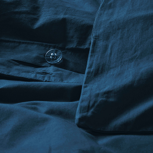 Primer plano de una funda nórdica azul oscuro con botón y tejido de algodón nítido. El tejido parece duradero y suave, con un acabado mate.
