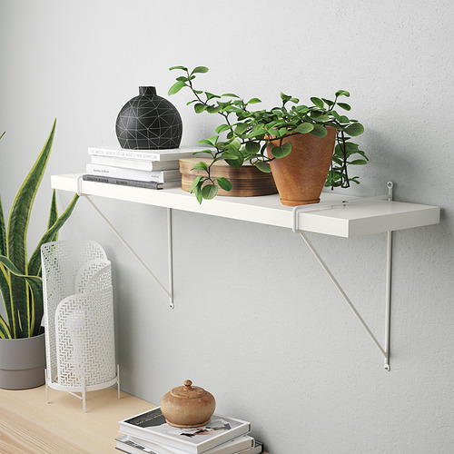 Estantería con jarrón, planta, libros en pared gris.