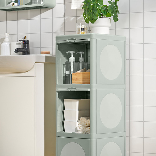 Mueble de baño IVÖSJÖN verde para guardar botellas, toallas y una planta.