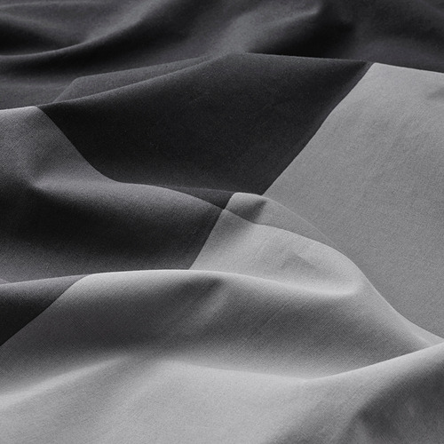 Primer plano en blanco y negro de la tela doblada, mostrando una textura fina y calidad.