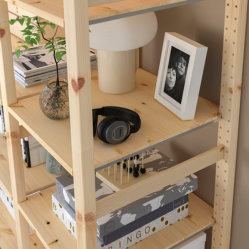 Estantería de madera con objetos: planta, lámpara, foto, auriculares y cajas.