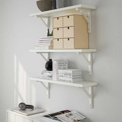 Un estante blanco montado en la pared con cajas de almacenamiento de madera, libros y un jarrón decorativo negro, que exhibe y organiza los artículos de manera ordenada.