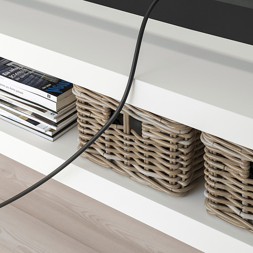 Mueble de TV moderno con cestas tejidas y libros. Gestión de cables visible, manteniendo los elementos organizados.