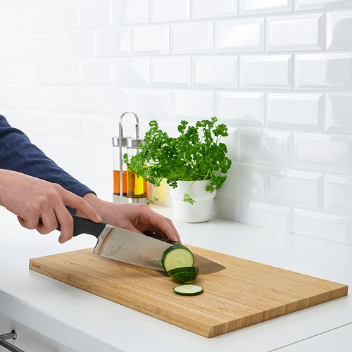 Persona cortando pepino en una tabla de cortar de madera con un cuchillo VÖRDA afilado y resistente.