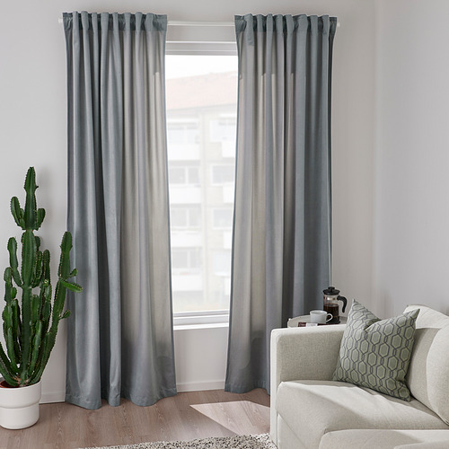 Cortinas azules de poliéster reciclado que enmarcan el paisaje urbano, con cactus y sofá.