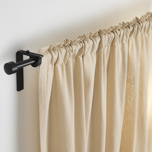 Barra de cortina de metal negro que sostiene cortinas beige, longitud ajustable con soporte elegante.
