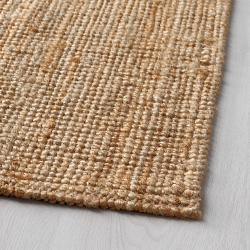 Primer plano de una alfombra natural de textura beige con intrincados patrones de tejido, que muestra material de yute de alta calidad.