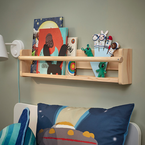 Estantería con libros de colores, juguetes, alienígena AFTONSPARV, libro joki, almohada espacial sobre la cama.