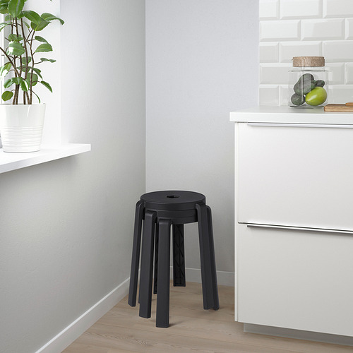 Pequeña cocina moderna con taburete apilable negro contra armario blanco.