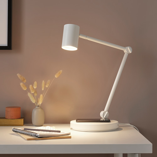 Moderna lámpara de escritorio blanca con brazo ajustable, flores y cuaderno.