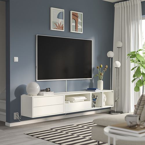 Modern living room: flat tv on white stand, blue wall, white decor, large rug.