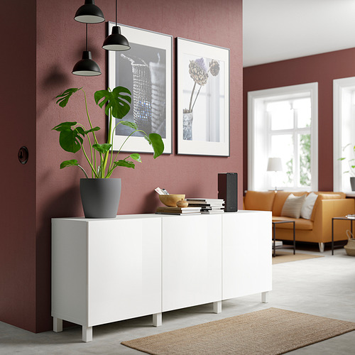 Aparador blanco BESTÅ en la habitación con paredes rojas, planta de sujeción y libros.