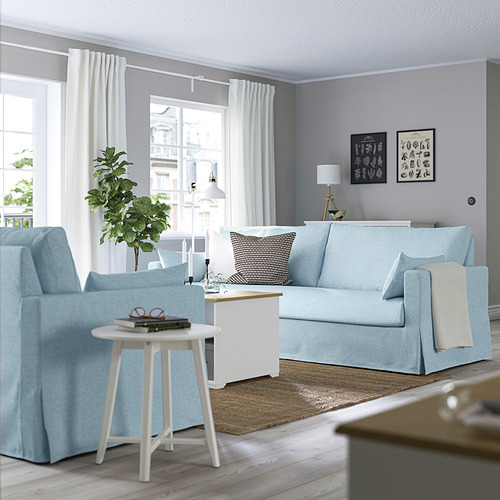 Salón moderno con muebles azules, grandes ventanales, luz natural.