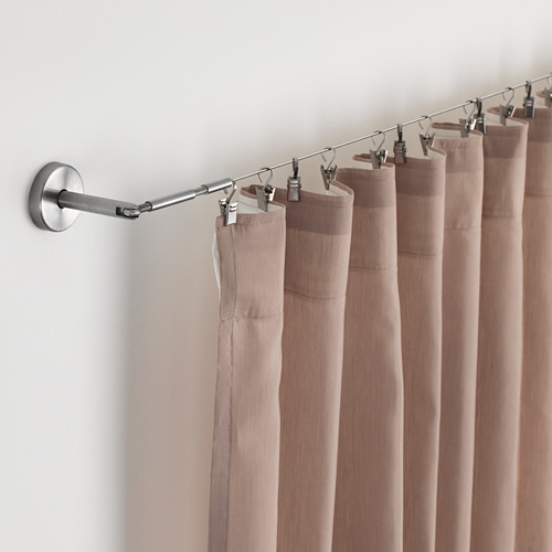 Barra de cortina con cortinas beige, fijada a la pared con herrajes ajustables.