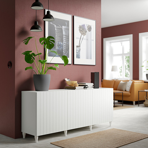 Aparador blanco BESTÅ con planta, pared burdeos, luces negras, estampados, sofá amarillo.