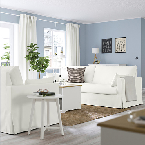 Sala de estar moderna con sofá blanco HYLTARP, vista a la ciudad, decoración minimalista.